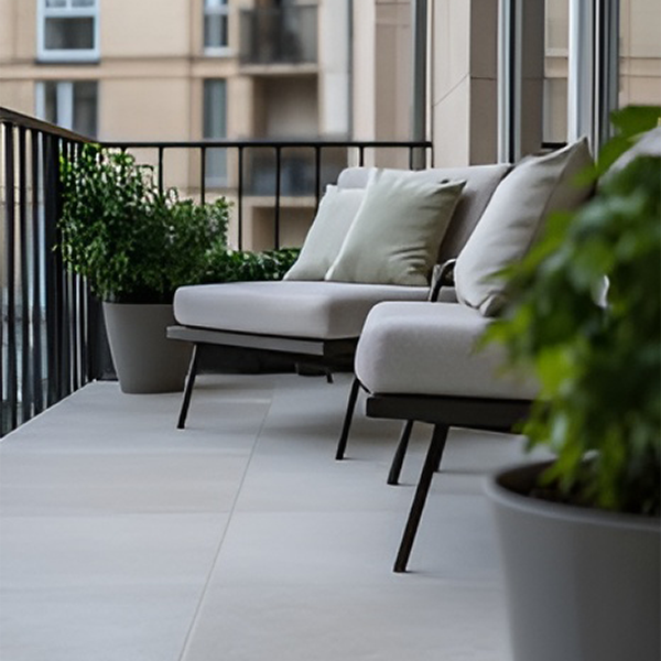 Erweiterter Balkon mit modernen, großformatigen, hellen Fliesen und stabiler Brüstung.